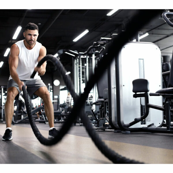 Sportler führt intensives Battle-Rope-Training im Gym für Ausdauer und Kraft durch.