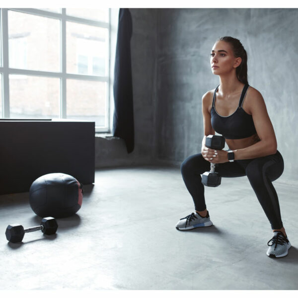 Frau beim Training mit Hexagon-Hanteln im Fitnessstudio