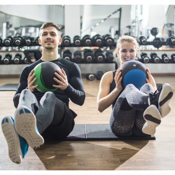 Zwei Sportler trainieren mit Medizinbällen für Kraft, Ausdauer und Stabilität.