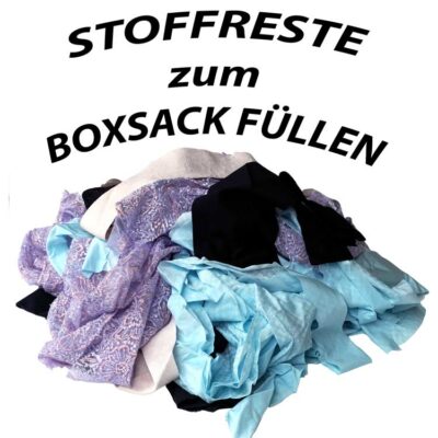 Ein Haufen ungeschnittener Stoffreste in verschiedenen Farben, darunter Blau und Lila, mit dem Schriftzug 'Stoffreste zum Boxsack füllen' darüber, auf weißem Hintergrund.
