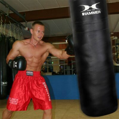 Trainingshandschuhe im Einsatz: Boxer trainiert mit HAMMER BOXING Handschuhen am Sandsack.