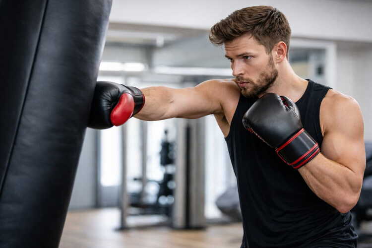 Boxsack Training im Fitnessstudio mit Boxhandschuhen – Mann trainiert Schlagtechnik und Kraft am hängenden Boxsack.